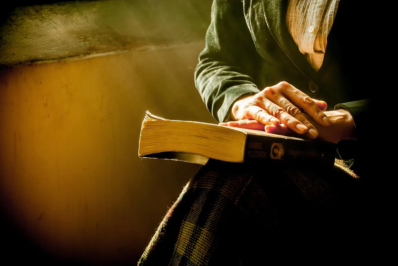 An open Bible beside a notebook with a reading schedule and completed check marks.